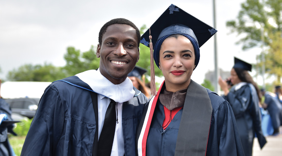 Two BIPOC students wearing graduation apparel